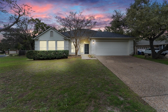 single story home featuring a garage and a lawn