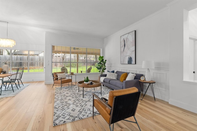 living room with hardwood / wood-style flooring, a wealth of natural light, crown molding, and a chandelier