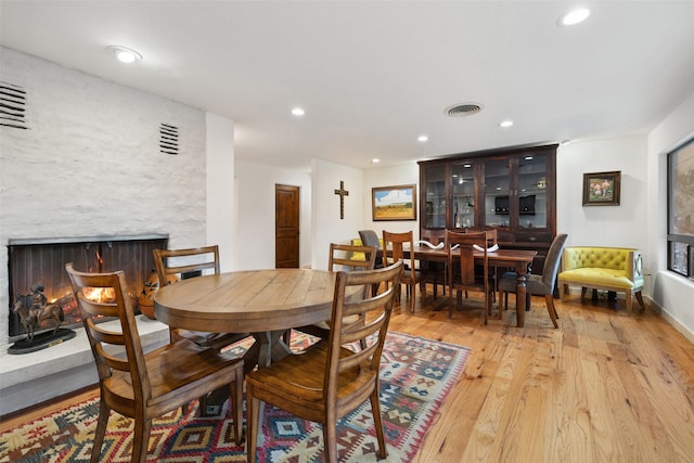 dining space with light wood-type flooring and a large fireplace