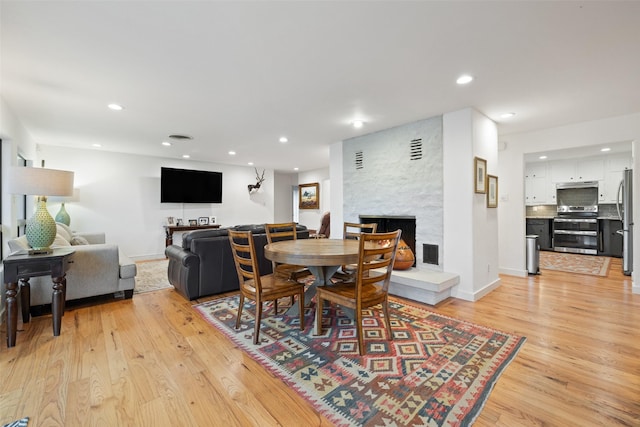 dining room featuring light hardwood / wood-style flooring and a fireplace