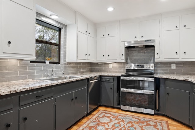 kitchen with white cabinetry, light hardwood / wood-style floors, stainless steel appliances, light stone counters, and sink