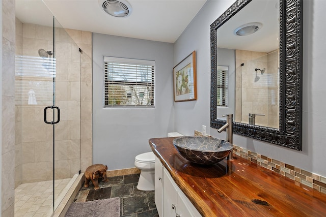 bathroom with toilet, vanity, and a shower with door