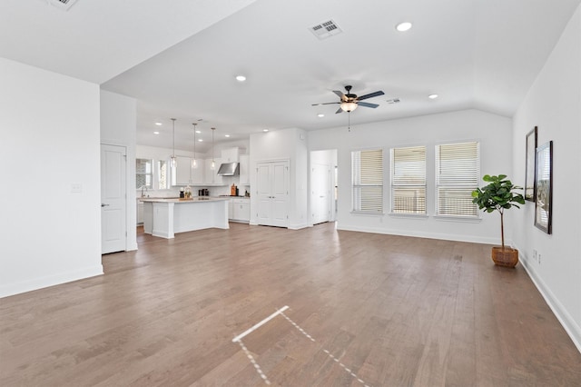 unfurnished living room with vaulted ceiling, ceiling fan, and wood-type flooring