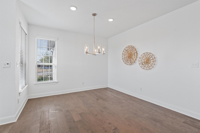 spare room featuring dark hardwood / wood-style floors and an inviting chandelier