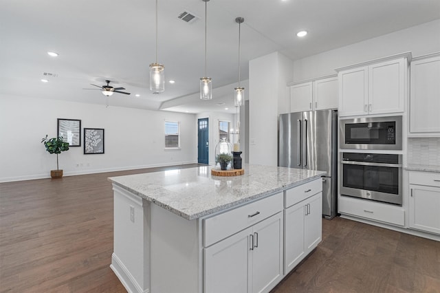 kitchen with ceiling fan, a kitchen island, decorative backsplash, stainless steel appliances, and white cabinets