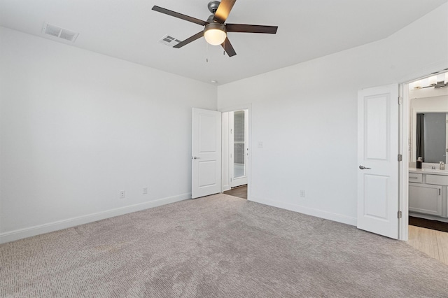 unfurnished bedroom with ceiling fan, light colored carpet, sink, and ensuite bath