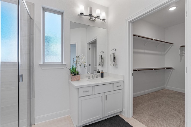 bathroom featuring a shower with shower door and vanity