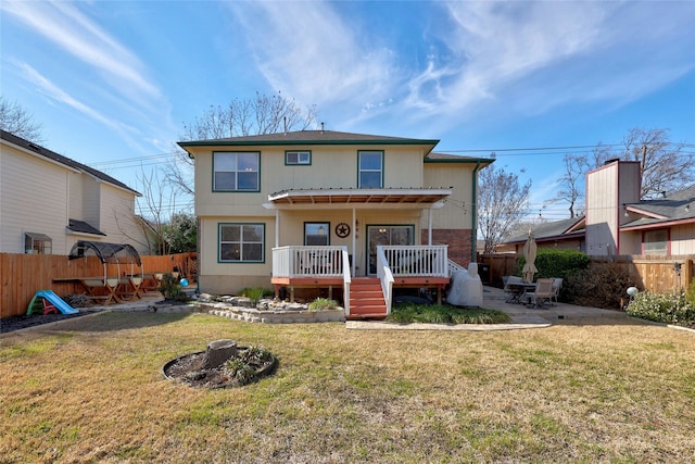 back of property with a lawn, a patio area, and a wooden deck