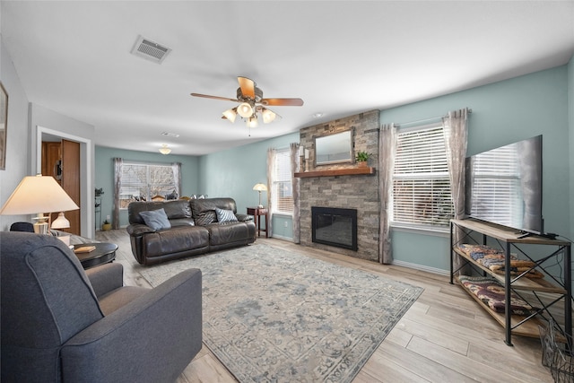 living room featuring ceiling fan, plenty of natural light, light hardwood / wood-style flooring, and a fireplace