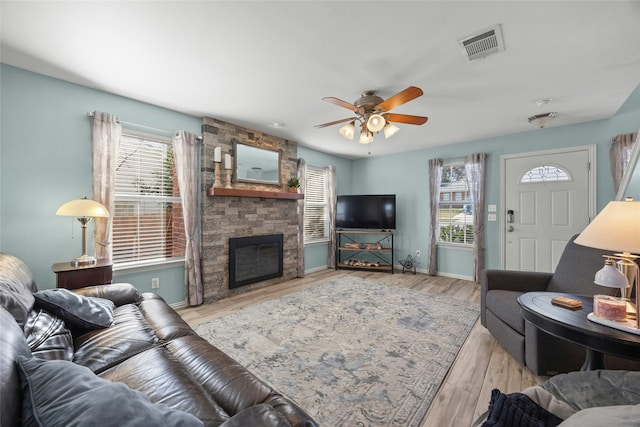 living room featuring ceiling fan, light hardwood / wood-style flooring, and a fireplace