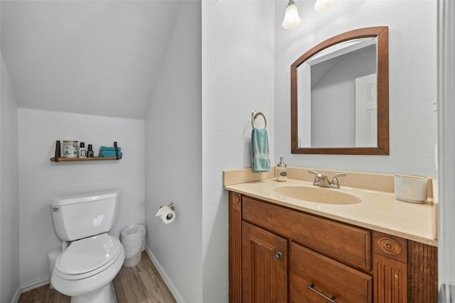 bathroom with toilet, vanity, vaulted ceiling, and hardwood / wood-style flooring