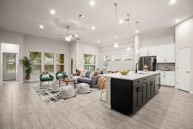 kitchen with ceiling fan, pendant lighting, a center island with sink, appliances with stainless steel finishes, and white cabinets