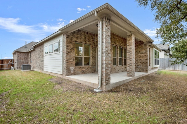 rear view of house featuring a lawn, central AC unit, and a patio