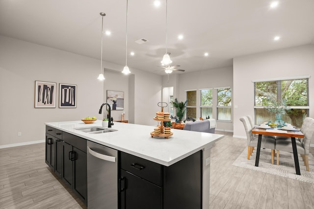 kitchen with sink, hanging light fixtures, stainless steel dishwasher, and a kitchen island with sink