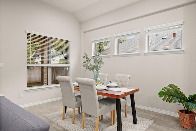 dining space featuring vaulted ceiling and light wood-type flooring