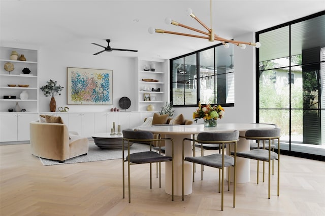 dining space featuring light parquet floors, a healthy amount of sunlight, and ceiling fan with notable chandelier