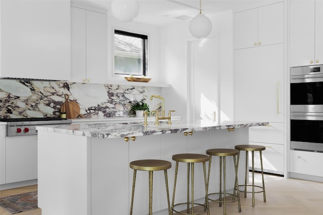 kitchen with stainless steel double oven, decorative backsplash, and white cabinetry