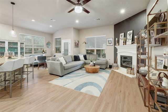 living room featuring ceiling fan, vaulted ceiling, and light wood-type flooring