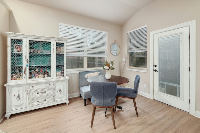 dining room with light wood-type flooring and vaulted ceiling