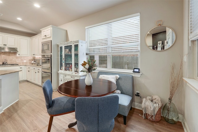 dining area with vaulted ceiling and light hardwood / wood-style floors