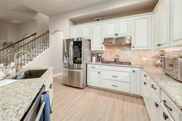 kitchen featuring light stone counters, sink, white cabinets, and appliances with stainless steel finishes