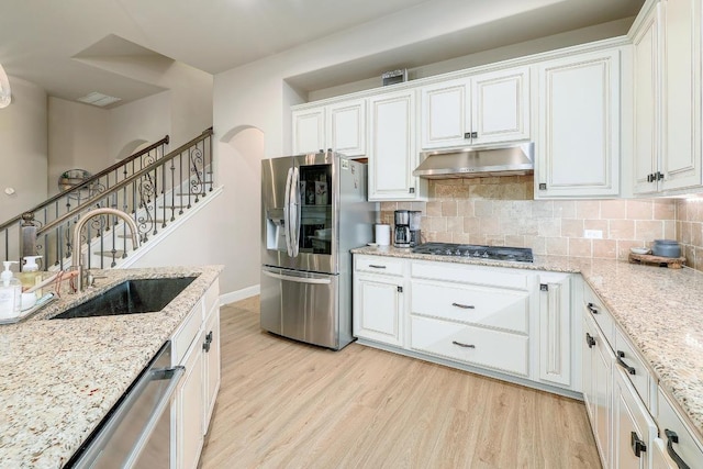 4408 Trinity Woods St, Leander, TX 78641 - kitchen featuring stainless steel appliances, under cabinet range hood, a sink, light wood-style floors, and white cabinets