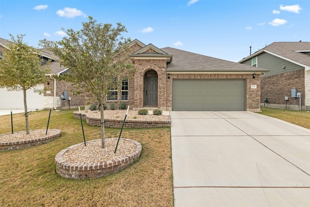 view of front of home featuring a front lawn, roof with shingles, concrete driveway, an attached garage, and brick siding