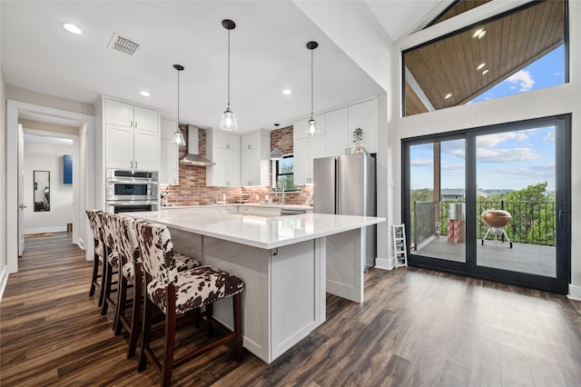 kitchen with a kitchen island, white cabinetry, lofted ceiling, stainless steel appliances, and wall chimney exhaust hood