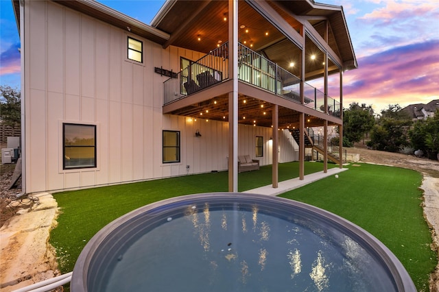 back house at dusk with a lawn and a pool