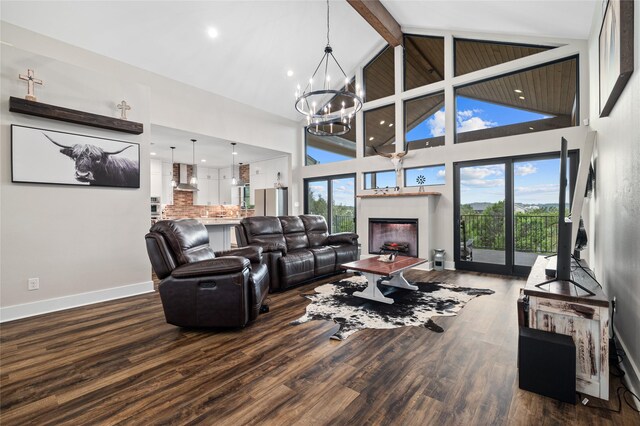 living room with high vaulted ceiling, plenty of natural light, hardwood / wood-style floors, and an inviting chandelier