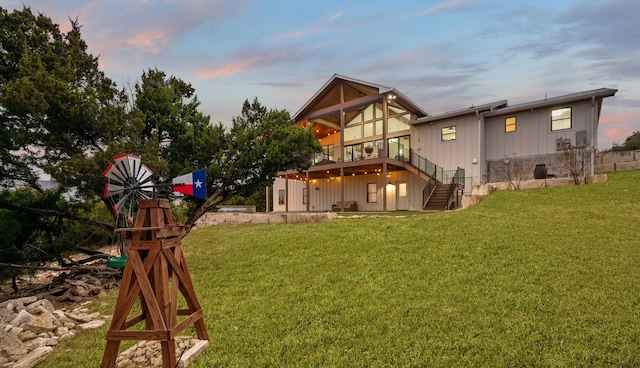 back house at dusk featuring a wooden deck and a lawn