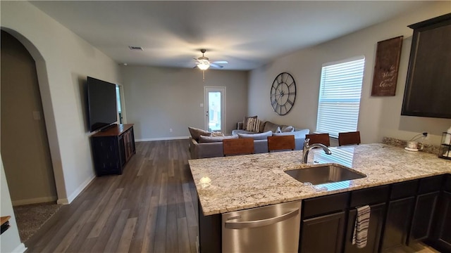 kitchen with ceiling fan, dark hardwood / wood-style floors, stainless steel dishwasher, sink, and light stone countertops