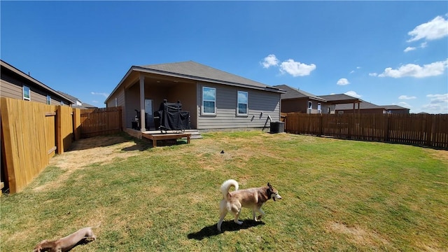 rear view of house featuring central AC unit and a lawn