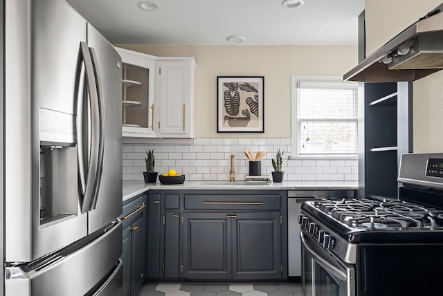 kitchen featuring gray cabinetry, white cabinetry, island range hood, appliances with stainless steel finishes, and decorative backsplash