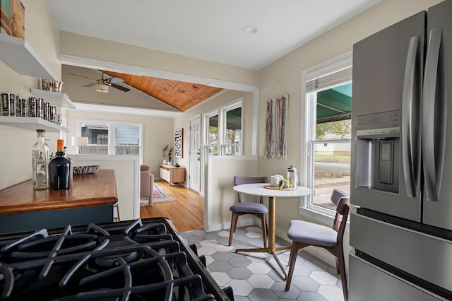 kitchen with vaulted ceiling, stainless steel fridge, ceiling fan, wood ceiling, and cooktop