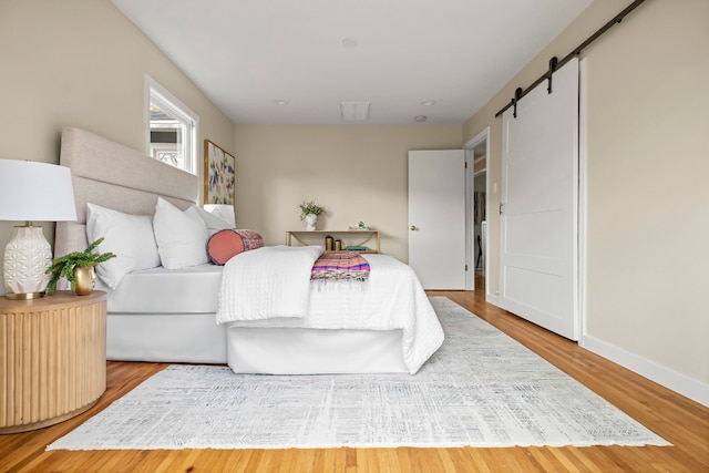 bedroom featuring wood-type flooring and a barn door