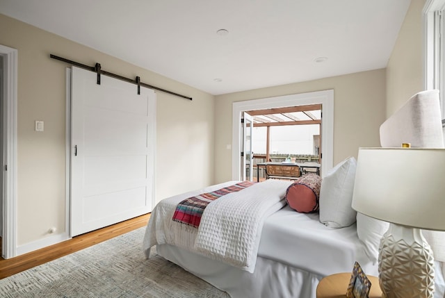 bedroom featuring wood-type flooring and a barn door