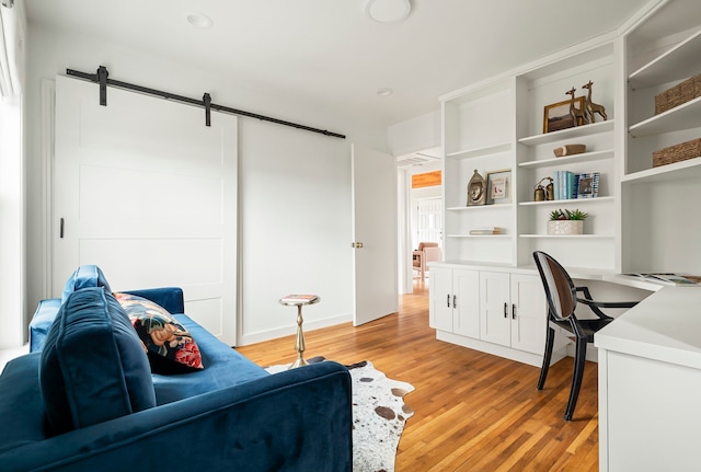 office with a barn door, built in desk, and light wood-type flooring