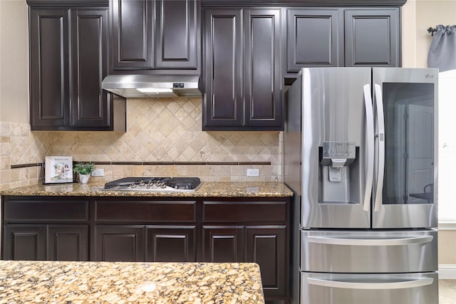 kitchen with light stone countertops, dark brown cabinets, backsplash, and stainless steel appliances