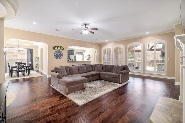 living room featuring dark wood-type flooring, crown molding, and ceiling fan with notable chandelier