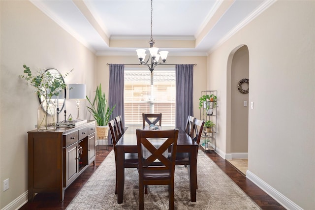 dining room featuring dark hardwood / wood-style floors, crown molding, a raised ceiling, and a notable chandelier