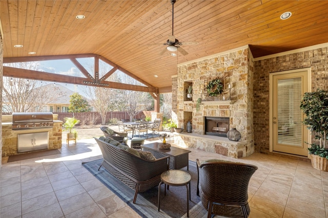 view of patio / terrace featuring area for grilling, exterior kitchen, ceiling fan, and an outdoor stone fireplace