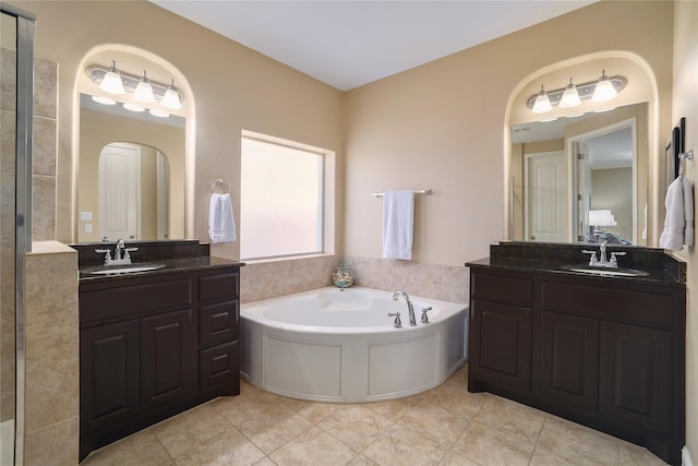 bathroom with tile patterned flooring, a tub to relax in, and vanity