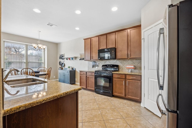 kitchen with black appliances, sink, hanging light fixtures, light stone countertops, and a chandelier