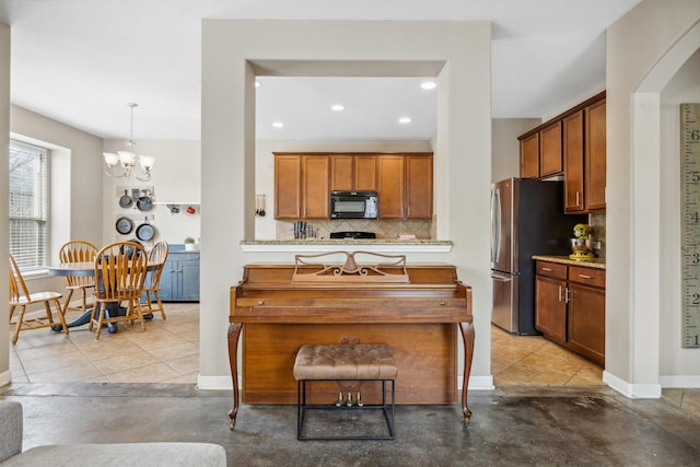 kitchen featuring light tile patterned floors, tasteful backsplash, hanging light fixtures, stainless steel refrigerator, and a chandelier