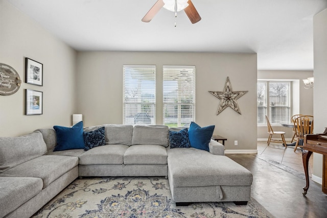 living room with a wealth of natural light and ceiling fan with notable chandelier