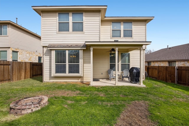 back of house with ceiling fan, a patio area, an outdoor fire pit, and a yard