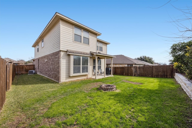 back of house featuring cooling unit, an outdoor fire pit, and a lawn