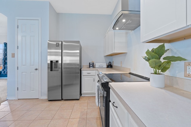 kitchen with range hood, light tile patterned floors, appliances with stainless steel finishes, and white cabinetry