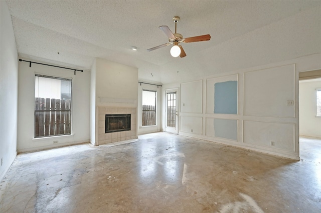 unfurnished living room featuring ceiling fan, a textured ceiling, a tile fireplace, and a healthy amount of sunlight